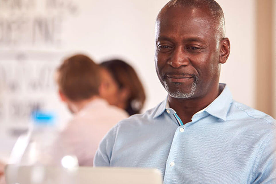 Mature Businessman With Laptop Working On Table In Office