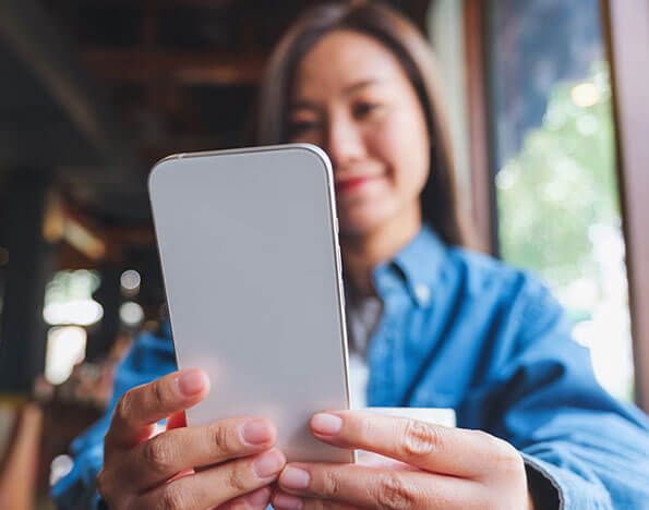 Blurred image of a young woman holding and using mobile phone