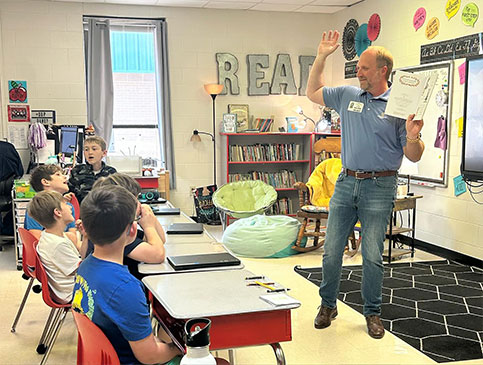 Armor Bank Team member reading to children in a classroom.