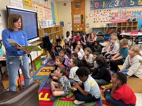 Armor Bank Team member reading a book to children.