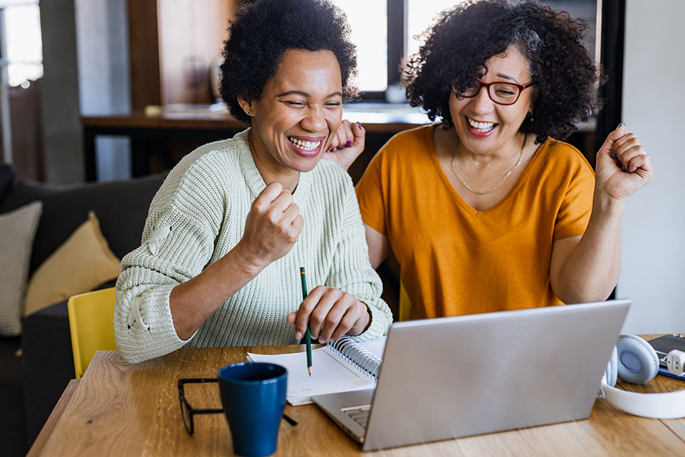 Two ladies working on a computer together.