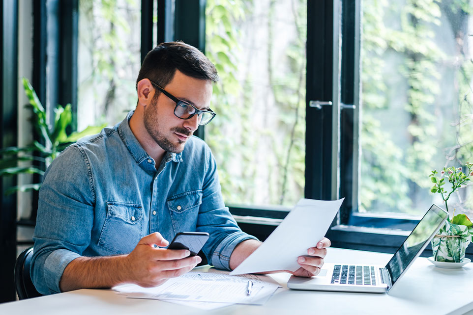 Man reviewing paperwork in front of computer