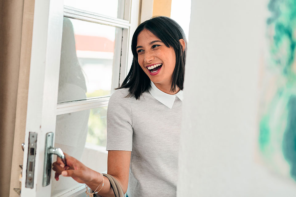 Young adult walking through their front door.